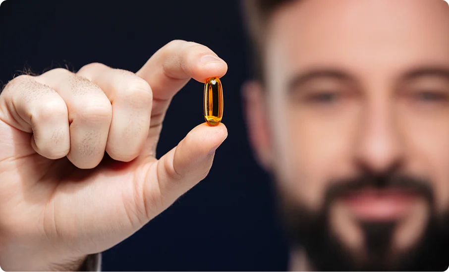 Man holding a golden supplement capsule